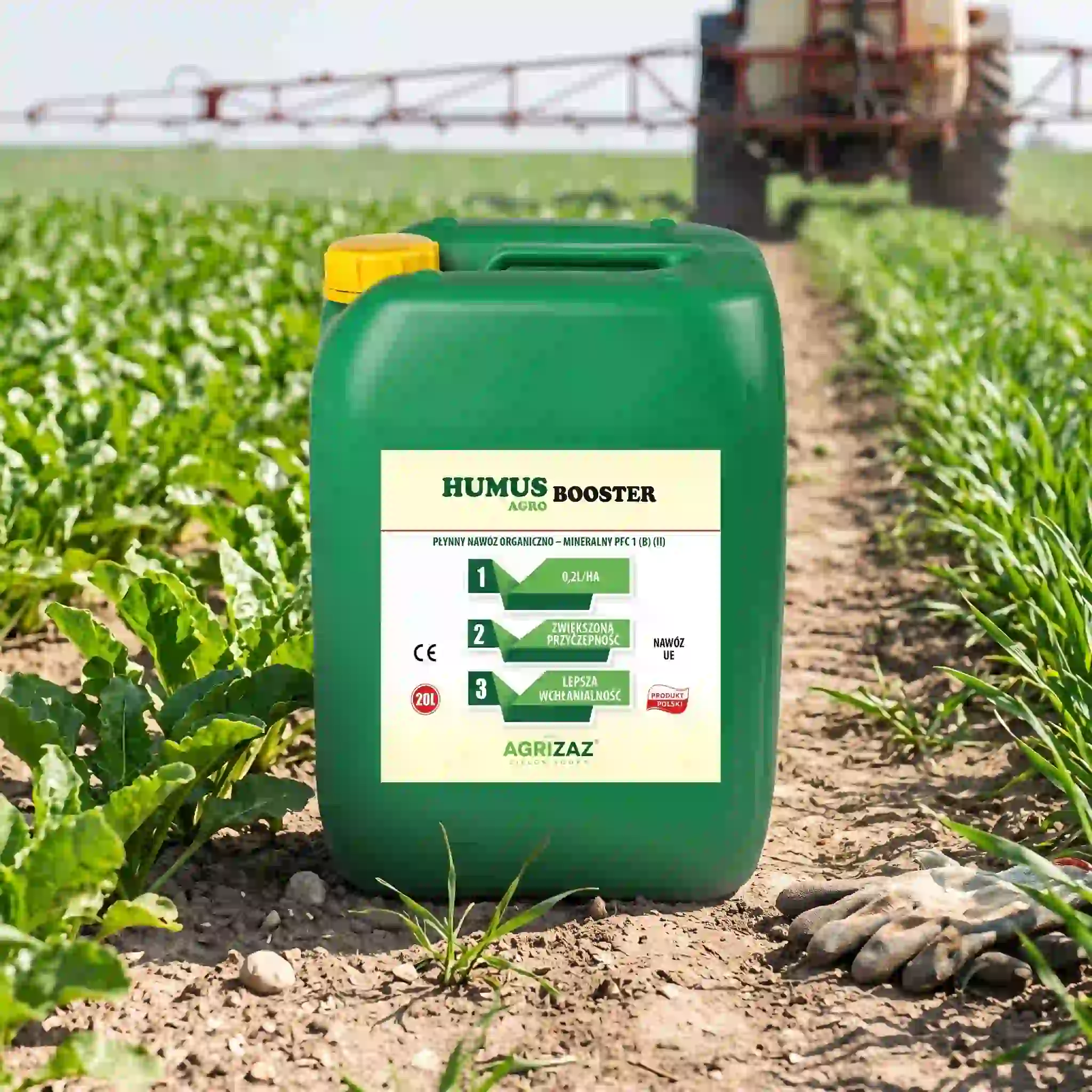 Zielony kanister 20L nawozu Humus Booster Agro marki Agrizaz stojący na ziemi w polu, z opryskiwaczem rolniczym w tle