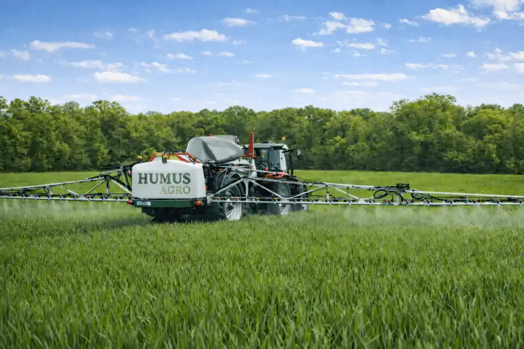 Traktor wykonujący oprysk na polu opryskiwaczem HUMUS AGRO